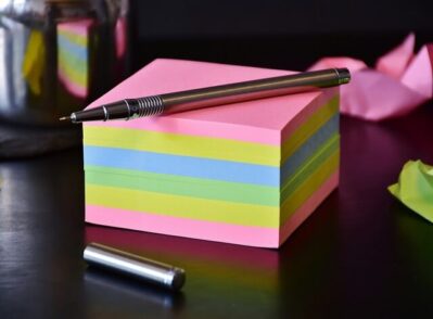 bloco de notas com folhas coloridas e caneta